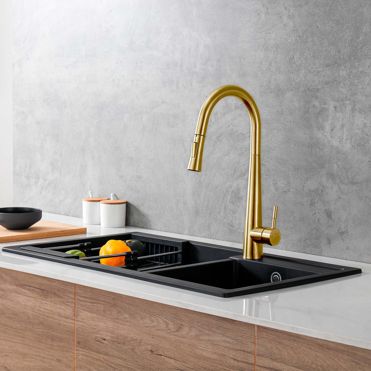 Modern kitchen sink with gold faucet against a gray wall.