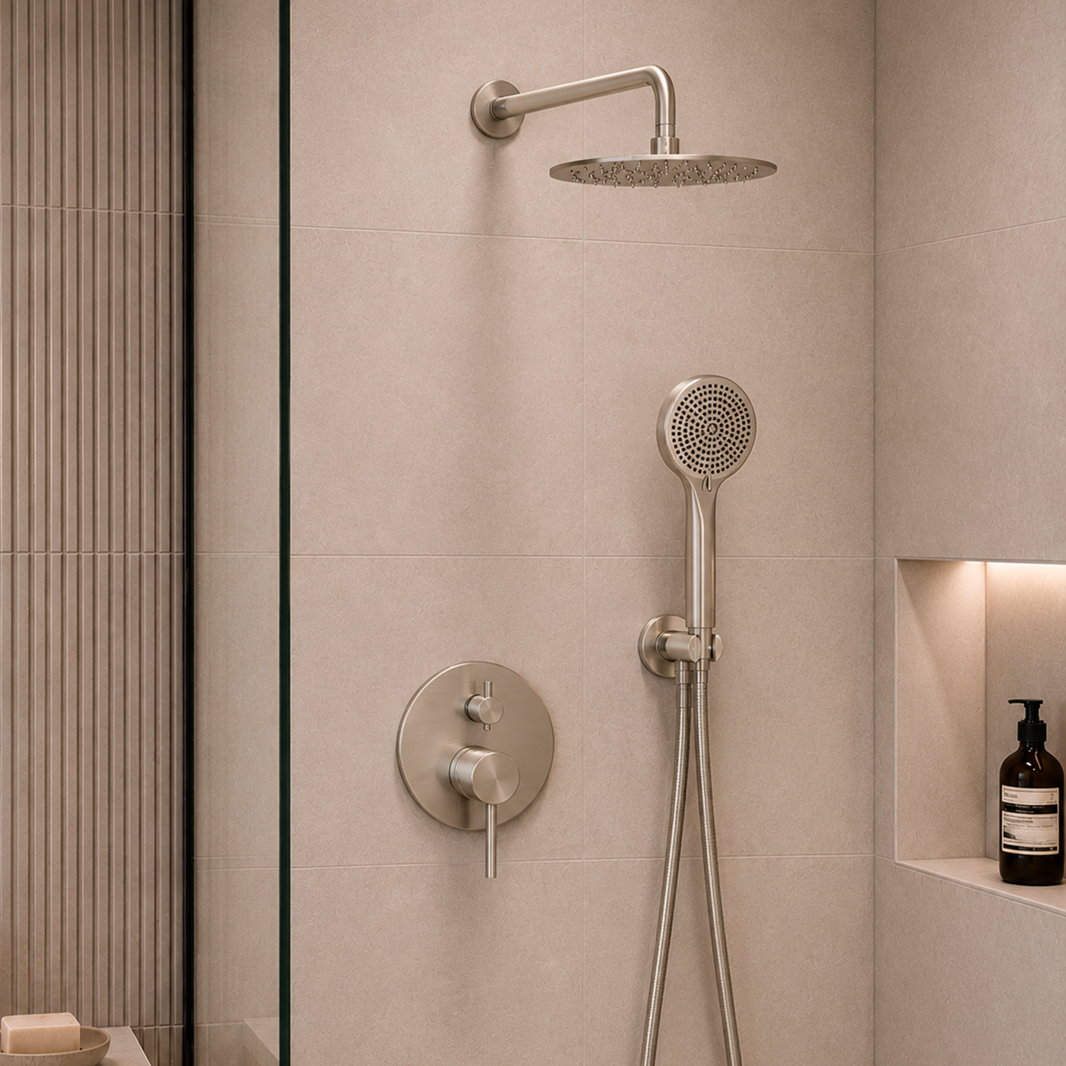 A modern shower fixture set in a tiled bathroom, featuring a round overhead rain shower head, a handheld shower wand with a flexible hose, and a matching round control valve on a beige stone wall.